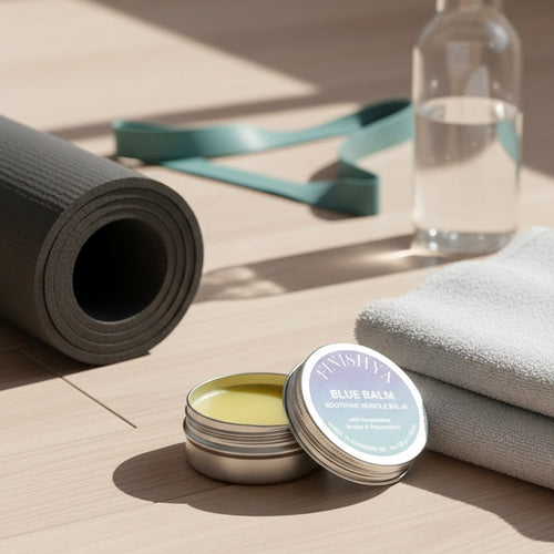 Finishya Blue Balm soothing muscle balm placed next to a rolled yoga mat and water bottle for post-workout recovery.