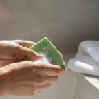 Hands lathering a green Finishya Jasmine soap bar under running water, highlighting its creamy foam and vegan formula.