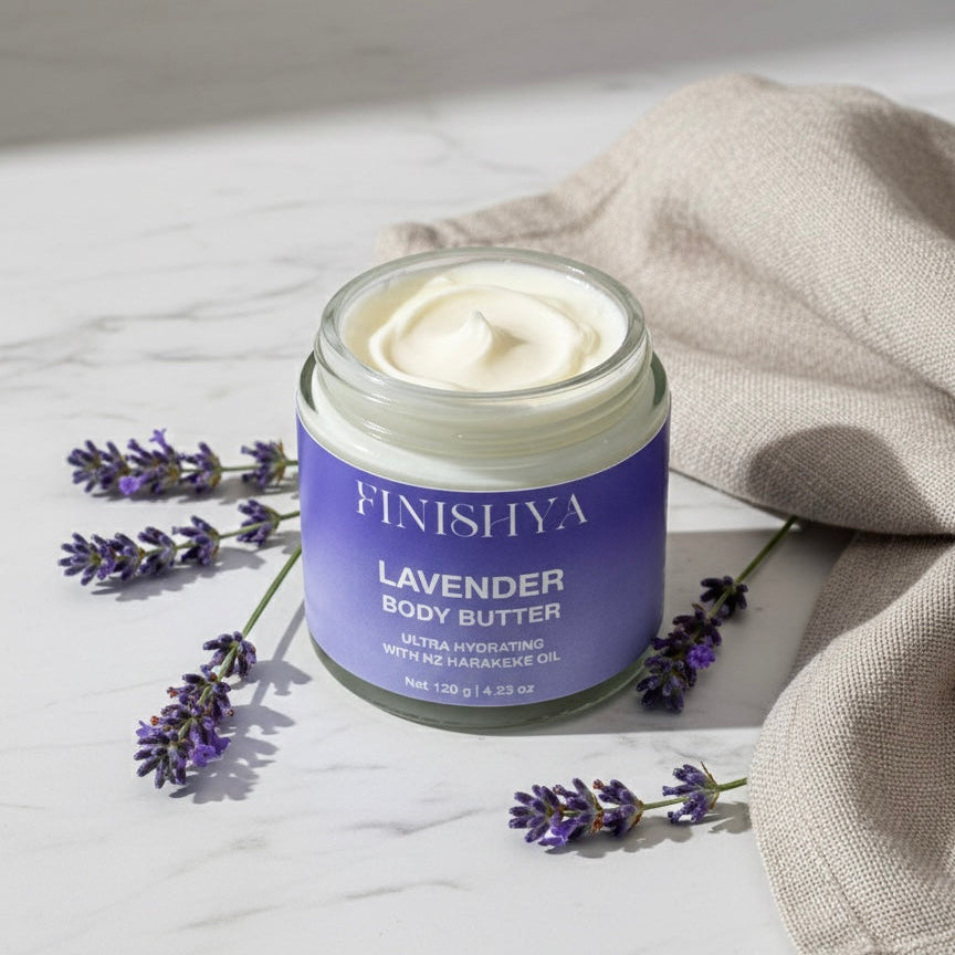 An open glass jar of Finishya Lavender Body Butter with NZ Harakeke Oil, surrounded by fresh lavender sprigs on a white marble tabletop. The product is vegan, cruelty-free, and designed for sensitive skin.