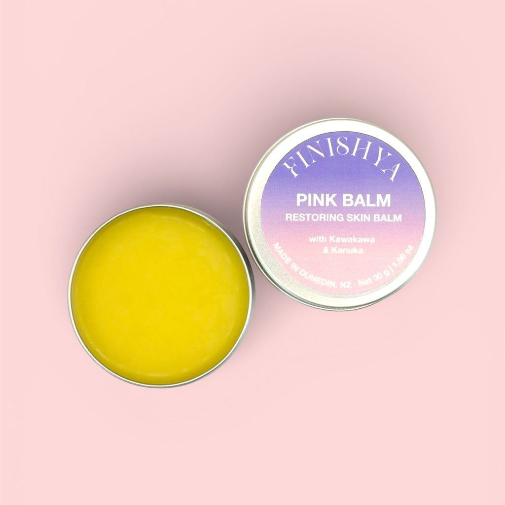 Top-down view of an open Finishya Pink Balm tin showing the smooth yellow texture, a vegan restoring skin balm made in Dunedin, NZ.