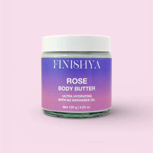 A front-facing product shot of Finishya Rose Body Butter in a glass jar against a soft pink background. The label highlights it as an ultra-hydrating, vegan moisturiser with NZ Harakeke oil.
