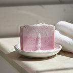 Close-up of bubbles on a pink Finishya Rose soap bar sitting on a white dish, demonstrating a rich lather for sensitive skin.