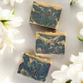 NES Midnight Bloom artisan soap bar surrounded by white flowers - scented with bergamot, gardenia, jasmine and sandalwood.