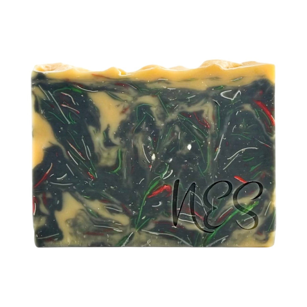 Close-up of NES Midnight Bloom handmade soap showing its dark floral swirl design with hints of gold and red.
