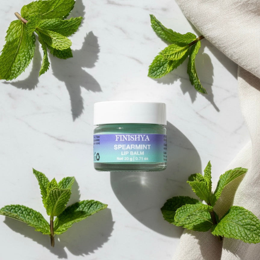 Finishya Spearmint Lip Balm jar styled with fresh mint leaves on marble, emphasising the refreshing fragrance and botanical ingredients.