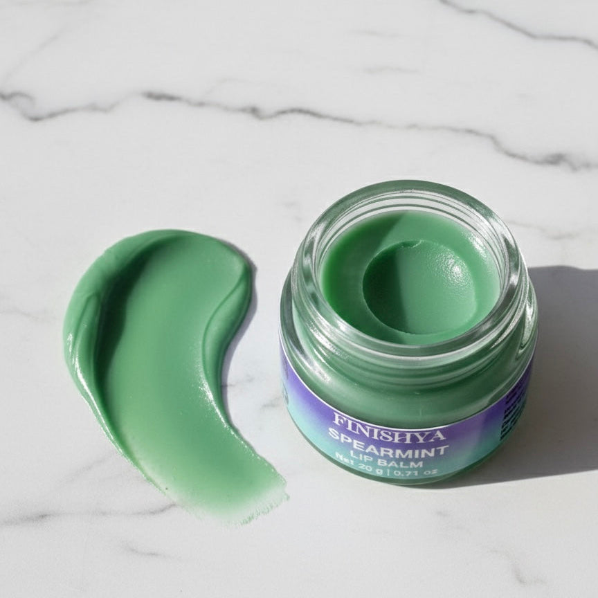 A smooth green texture swatch of Finishya Spearmint Lip Balm on a marble surface, showcasing its creamy consistency.