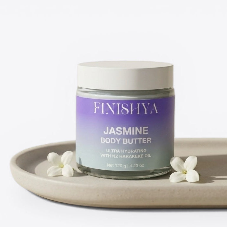 Finishya Jasmine Body Butter in a glass jar with white lid, featuring NZ Harakeke oil for sensitive skin, styled on a minimalist tray with white jasmine flowers.